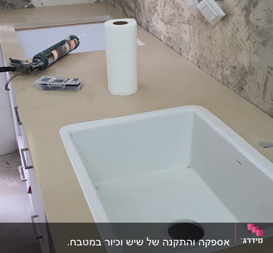 כיור לבן מותקן על משטח שיש במטבח